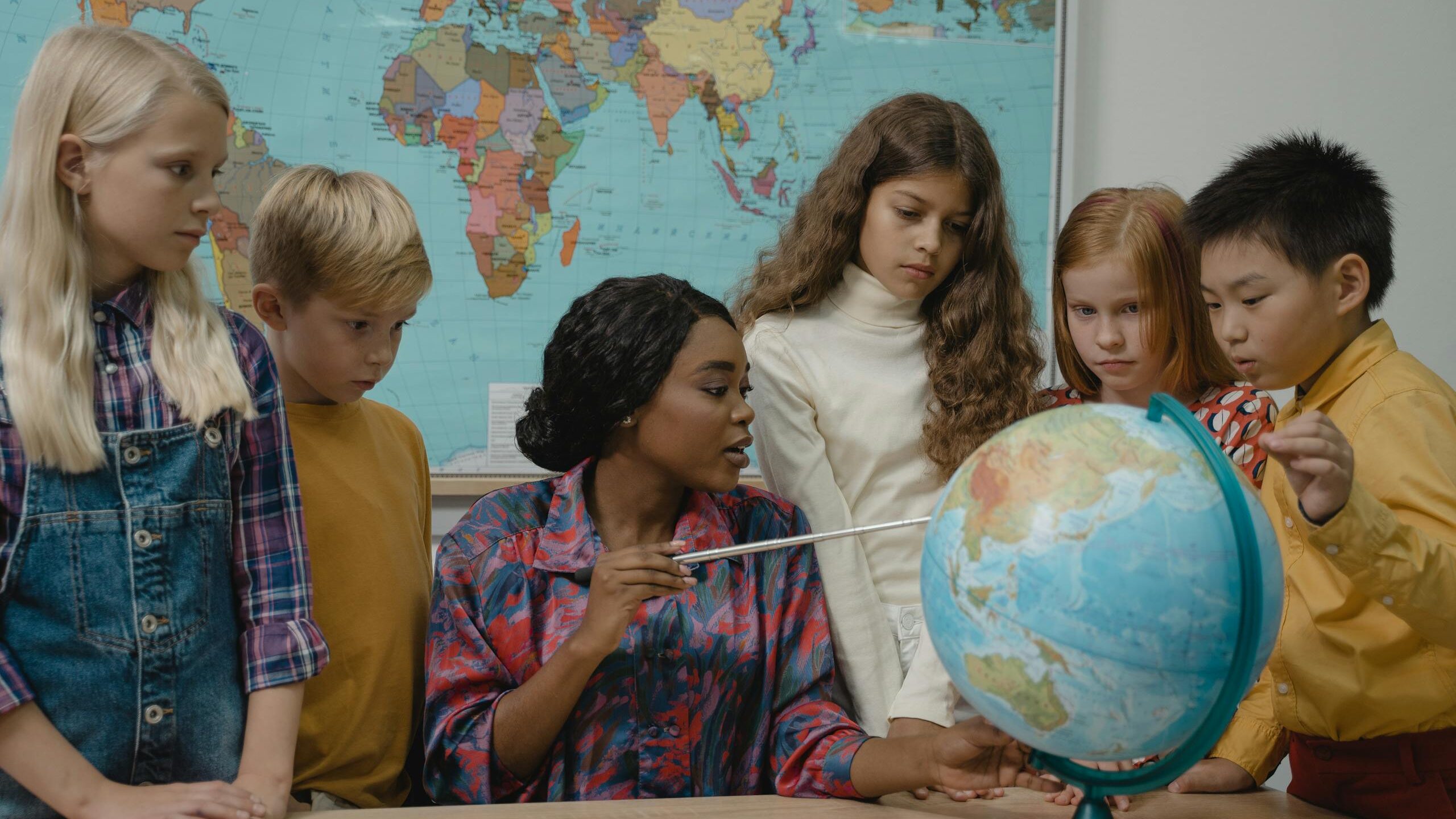 Teacher and students looking at globe, demonstrating classroom management as a possible digital product idea.