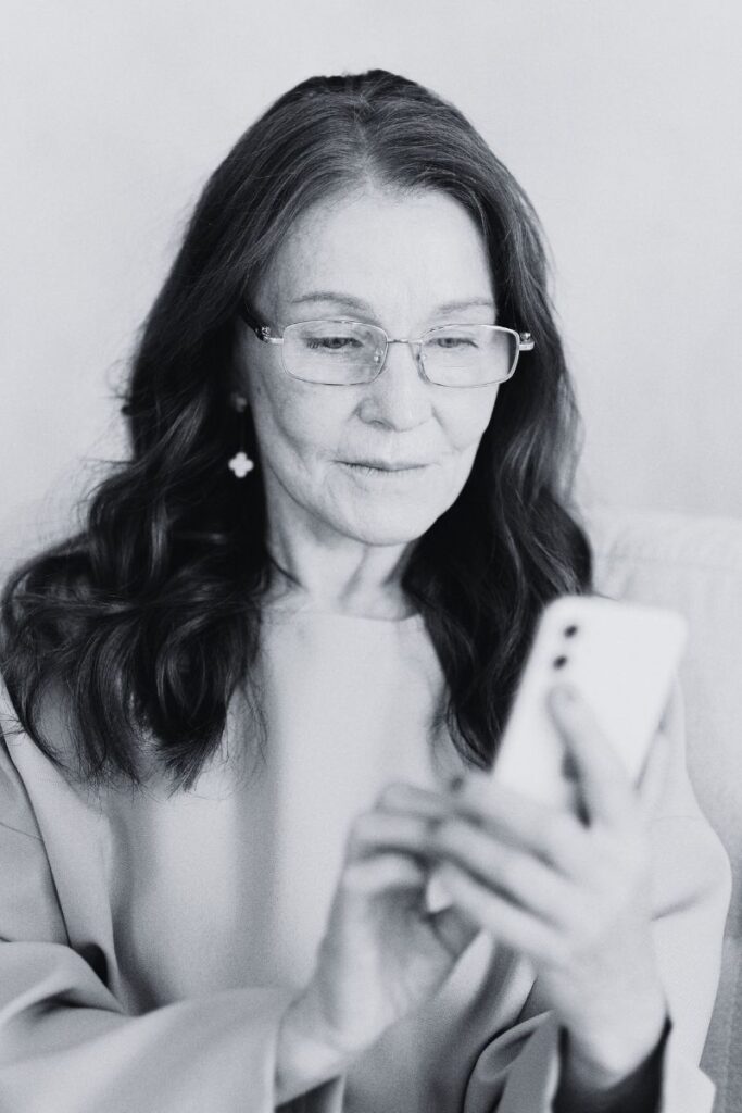 Senior woman with glasses looking at mobile device needs digital product accessibility for ebooks, courses, and video content