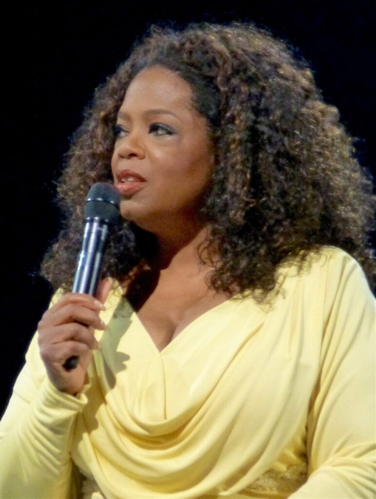 Find your expertise, Oprah Winfrey showing her expertise in speaking in 2014, yellow dress holding microphoe 